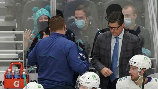 Seattle Kraken fan Nadia Popovici, upper left, gestures toward Vancouver Canucks assistant equipment manager Brian "Red" Hamilton, second from left, after they were introduced during the first period of an NHL hockey game. (AP) Seattle Kraken fan Nadia Popovici, upper left, gestures toward Vancouver Canucks assistant equipment manager Brian "Red" Hamilton, second from left, after they were introduced during the first period of an NHL hockey game. (AP)