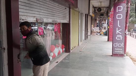 A shopkeeper downing the shutter in Panchkula in view of Haryana government’s order to close markets by 5pm. (Sant Arora/HT)