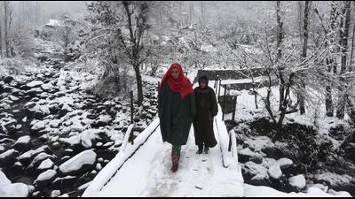 Locals cross a snow-covered bridge in Srinagar on Tuesday. (Waseem Andrabi/Hindustan Times)