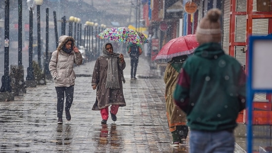 People in warm clothes, step outside during the season's first snowfall in Srinagar.(PTI)