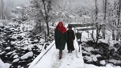 Locals cross a snow-covered bridge in Srinagar on Tuesday. (Waseem Andrabi/HT Photo)