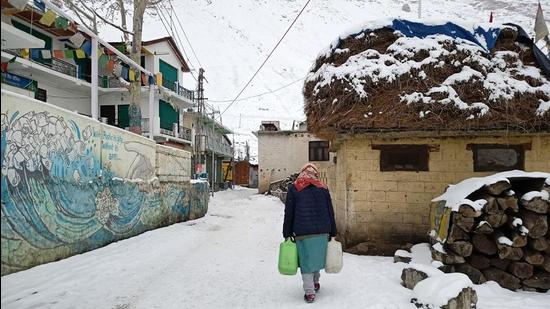 A woman carries water through a snow-covered road in Kaza village of Spiti valley in Himachal on Wednesday. (HT Photo)
