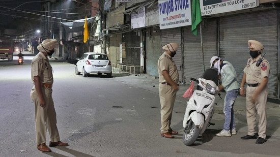 Punjab Police personnel checking the documents of a scooter rider during the night curfew in Ludhiana.(Gurpreet Singh/HT file photo)