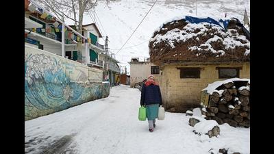 A woman carrying water through a snow-covered road at Kaza village in Spiti valley of Lahaul and Spiti district on Wednesday. (HT Photo)