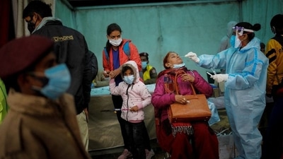 A healthcare worker collects a swab sample from a woman to test for Covic-19, at a railway station in New Delhi. (Reuters Photo)