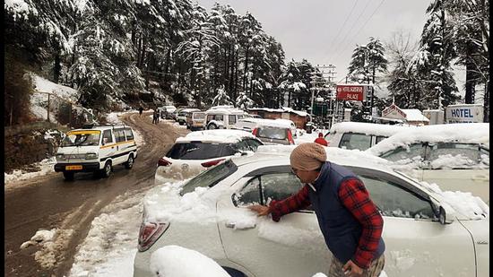 A man clears snow from his vehicle at snow-clad Patnitop as the higher reaches of Jammu and Kashmir receives fresh snowfall, in Ramban on Thursday. The MeT office has issued an orange level warning and predicted fresh heavy to very heavy snowfall. (ANI)