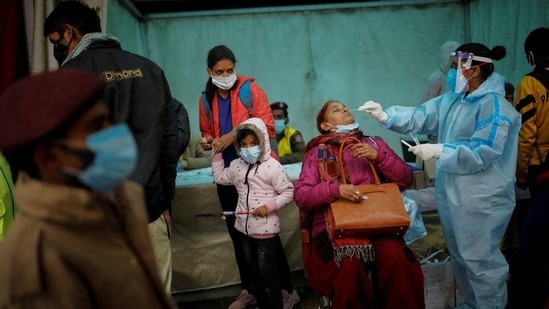 A healthcare worker collects a swab sample from a woman to test for Covic-19, at a railway station in New Delhi.(Reuters Photo)