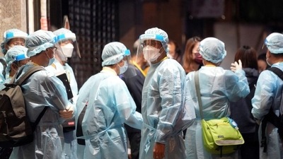 Workers wearing protective suits arrive to a building under lockdown for compulsory testing, following the coronavirus disease (COVID-19) outbreak in Hong Kong, China. (REUTERS)