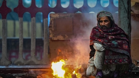 A man warms up by a fire on a cold, rainy winter's day in New Delhi on Saturday.  (PTI)