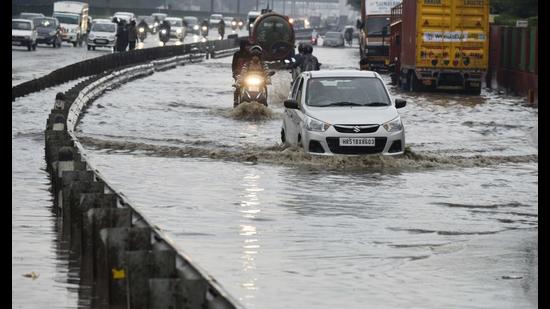 Vehicles wade through a waterlogged service lane of the Delhi-Gurugram Expressway near Narsinghpur village in Gurugram on Saturday. (Parveen Kumar/HT)