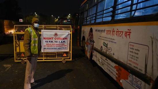 Police personnel stand guard at a road checkpoint near India Gate at the start of the weekend curfew in Delhi. (AFP Photo)