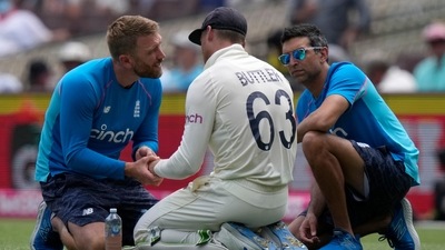 England's Jos Buttler, center, is treated for an injury in a break in play during the second day of their Ashes cricket test match against Australia in Sydney, Thursday, Jan. 6, 2022. (AP) England's Jos Buttler, center, is treated for an injury in a break in play during the second day of their Ashes cricket test match against Australia in Sydney, Thursday, Jan. 6, 2022. (AP)