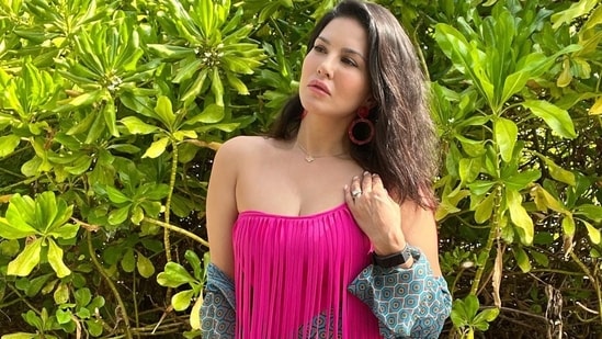 The monokini was layered with a matching blue print shrug that came with full sleeves.  Sunny left her mid-length braids open behind her back in a side-parted hairstyle as she posed in an exotic setting.  (Instagram / sunnyleone)