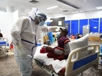 A health worker in a PPE kit checks a Covid-19 patient at Covid Care Centre, Commonwealth Games Village, in New Delhi on Wednesday.&nbsp;