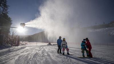 Snowboarders ride past a snow cannon at Wanlong Ski Resort in the Chongli district of Zhangjiakou, Hebei Province, China, on , January 3. (Bloomberg)