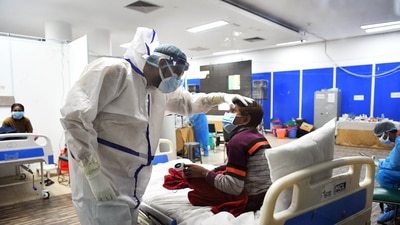 A health worker in a PPE kit checks a Covid-19 patient at Covid Care Centre, Commonwealth Games Village, in New Delhi on Wednesday. (Rahul Singh / ANI) A health worker in a PPE kit checks a Covid-19 patient at Covid Care Centre, Commonwealth Games Village, in New Delhi on Wednesday. (Rahul Singh / ANI)