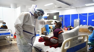 A health worker in a PPE kit checks a Covid-19 patient at Covid Care Centre, Commonwealth Games Village, in New Delhi. ( ANI) A health worker in a PPE kit checks a Covid-19 patient at Covid Care Centre, Commonwealth Games Village, in New Delhi. ( ANI)