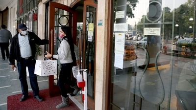 A woman leaves after picking up her order from a restaurant in Connaught Place as the Delhi government has shut down dine-in services in restaurants. (ANI Photo)