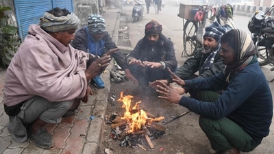 Vendors warm themselves around a bonfire during a cold foggy morning. (AFP)