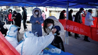 A medical worker in protective suit collects a swab from a resident for nucleic acid testing at a makeshift testing site for Covid-19), in Tianjin on Tuesday. (Reuters Photo)