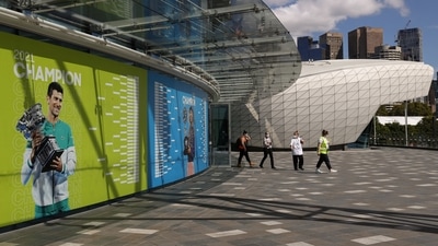 People exit a building with an image of Serbian tennis player Novak Djokovic as questions remain over the legal battle regarding his visa to play in the Australian Open, at Melbourne Park in Melbourne, Australia, January 12, 2022. (REUTERS)