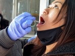 A health worker collects swab sample of a woman for the Covid-19 test, amid concerns over rising Omicron cases.