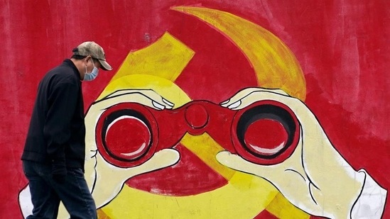 A man wears a mask as he walks past a mural showing a modified image of the Chinese Communist Party emblem in Shanghai, China.(REUTERS) A man wears a mask as he walks past a mural showing a modified image of the Chinese Communist Party emblem in Shanghai, China.(REUTERS)
