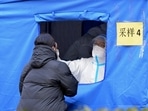 A medical worker wearing a protective suit swabs a woman for a coronavirus test in northern China's Tianjin municipality on Saturday. A medical worker wearing a protective suit swabs a woman for a coronavirus test in northern China's Tianjin municipality on Saturday. 