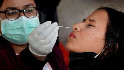 A healthcare worker collects a swab sample of a pedestrian for COVID-19 test, amid a surge in Omicron cases. (PTI) A healthcare worker collects a swab sample of a pedestrian for COVID-19 test, amid a surge in Omicron cases. (PTI)