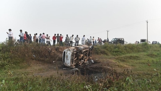 People take a look at the overturned car which was destroyed in violence during farmers' protest, at Tikonia area of Lakhimpur Kheri district, on October 4, 2021. (PTI)