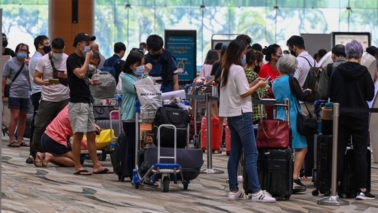 Passengers queue to check-in for their flights prior to departure.(AFP)