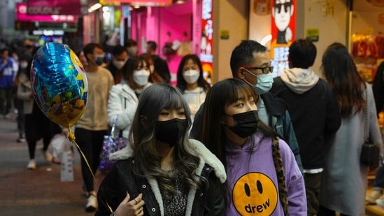 People wearing face masks to protect against the spread of the coronavirus, walk on a street in Hong Kong. Hong Kong International Airport said that it would ban passengers from over 150 countries and territories from transiting in the city for a month, as it sought to stem the transmission of the highly contagious Omicron variant of the coronavirus &nbsp;(AP Photo/Kin Cheung)