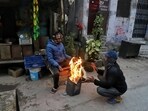 People sit around a bonfire to keep themselves warm on a cold winter morning, in New Delhi on Sunday. (Amit Sharma / ANI)