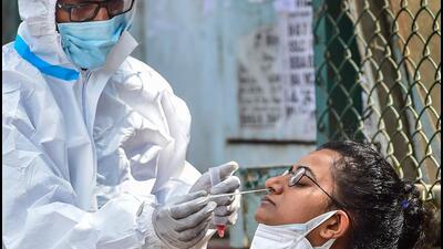 A health worker collects swab sample of passengers for Covid-19 test in Bengaluru on Sunday. (PTI) A health worker collects swab sample of passengers for Covid-19 test in Bengaluru on Sunday. (PTI)