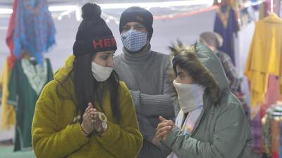 Women bundled up in woollens warming up their hands in Sector 34, Chandigarh, on a chilly Sunday evening. (Keshav Singh/HT)
