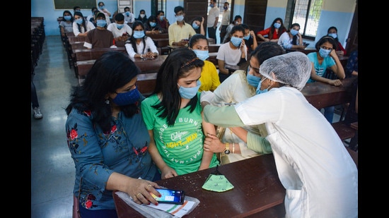 A Municipal Corporation worker administers a dose of Covid-19 vaccine to a teenager, at a municipal school in Thane. (PTI)