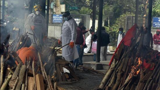 Volunteers and relatives perform the last rites of a Covid-19 victim, at Seemapuri cremation ground, in New Delhi. The new scheme also allows any Delhi resident who loses a family member or has lost a family member to Covid and is yet to get the ex-gratia to submit an application. (Raj K Raj/HT Photo)