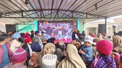 People watching the AAP announcement on a big screen at Bhagwant Mann’s native Satoj village in Sangrur. (HT Photo)