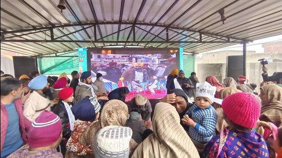 People watching the AAP announcement on a big screen at Bhagwant Mann’s native Satoj village in Sangrur. (HT Photo)