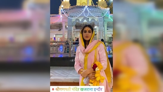 Donning a pink and yellow salwar suit and a garland in her hand, Sara Ali Khan posed for the camera with the temple in the backdrop.(Instagram/@saraalikhan95)