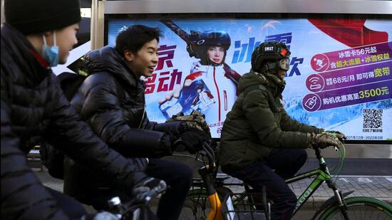 People ride bicycles past an advertisement at a bus stop in Beijing. China has coerced nearly 10,000 overseas nationals to return since 2014 using means and methods outside the justice system, according to Spain-based rights group Safeguard Defenders. (REUTERS)