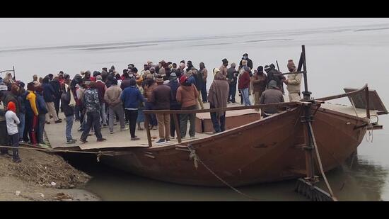 People gather at the site where a tractor trolley, carrying 14 people, toppled off a boat and fell into the Gandak river on Wednesday. (HT Photo)