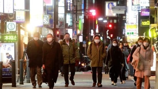 People wearing face masks, to help protect against the spread of the coronavirus, walk along a street lined with bars and restaurants in Tokyo. Tokyo and a dozen other areas in Japan are set to face new Covid-19 restrictions effective Friday, with local leaders shortening hours for restaurants, as Omicron cases hit a record high in the capital. &nbsp;(AP Photo/Koji Sasahara)