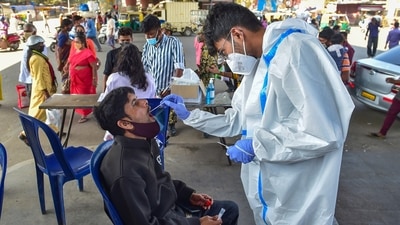 A health worker collects a swab sample of a commuter for the Covid-19 test at K R Market in Bengaluru on Thursday. (PTI) A health worker collects a swab sample of a commuter for the Covid-19 test at K R Market in Bengaluru on Thursday. (PTI)