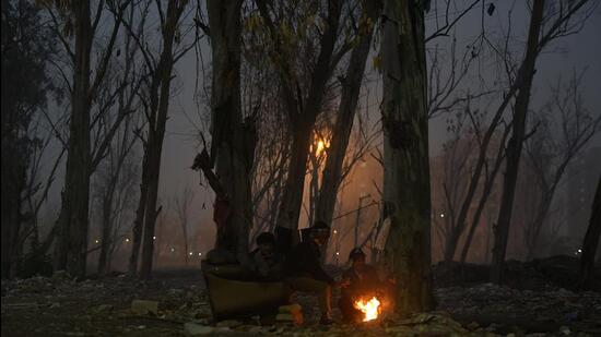 People huddle around a bonfire near Ghazipur in Delhi. (HT Photo)