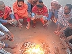 People warm themselves around a small fire on a cold winter morning.