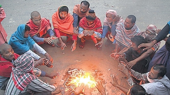 People warm themselves around a small fire on a cold winter morning.