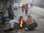 People huddle around a bonfire during light rainfall at Sadar Bazar in New Delhi.(HT Photo)