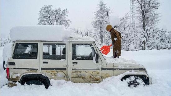 A boy uses a shovel to clear out snow from atop a vehicle after a snowfall at Hirpora village in south Kashmir’s Shopian district, 70 km from Srinagar, on Sunday. Traffic officials said that the Jammu-Srinagar National Highway was blocked owing to landslides after the snowfall during the night. (AFP)