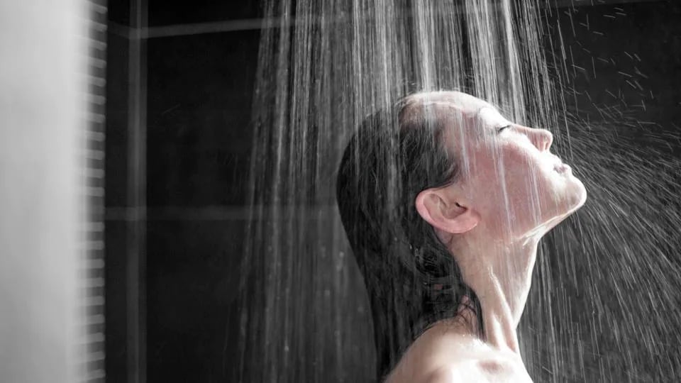 Morning shower.Taking rejuvenating cold shower.Self care moment.Everyday  personal hygiene.Unfocused woman showering in glass shower with strong  pressure water stream.Focus on drops Stock Photo